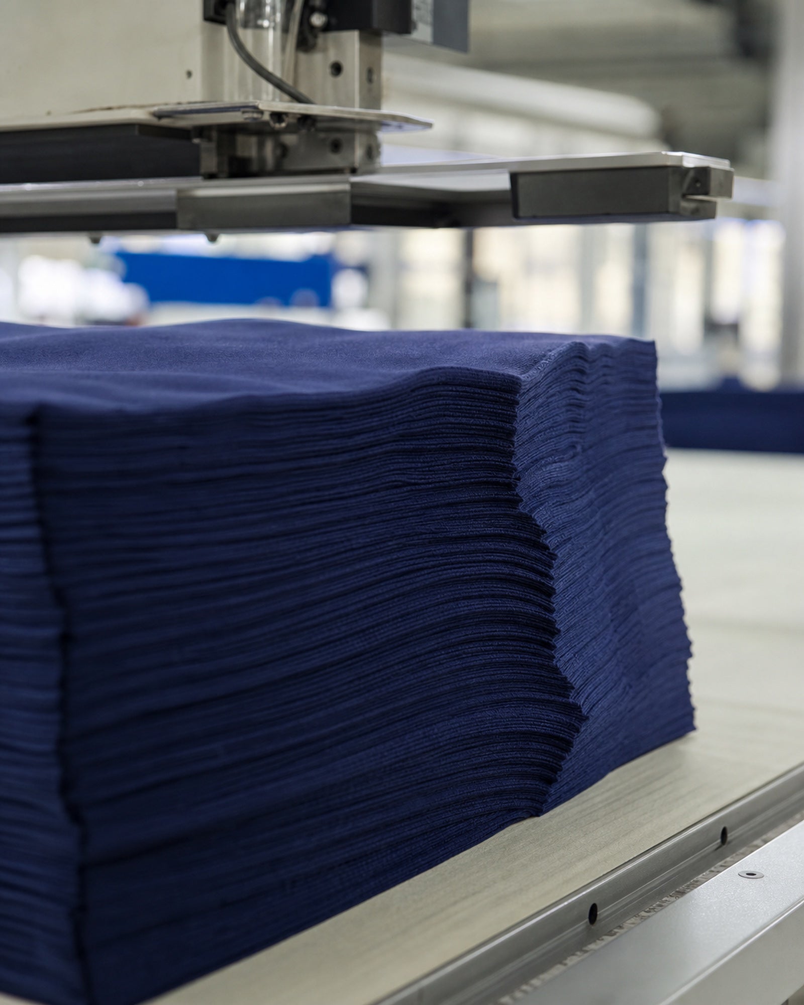 Stacked cotton fabric layers aligned for cutting in a garment factory production workflow