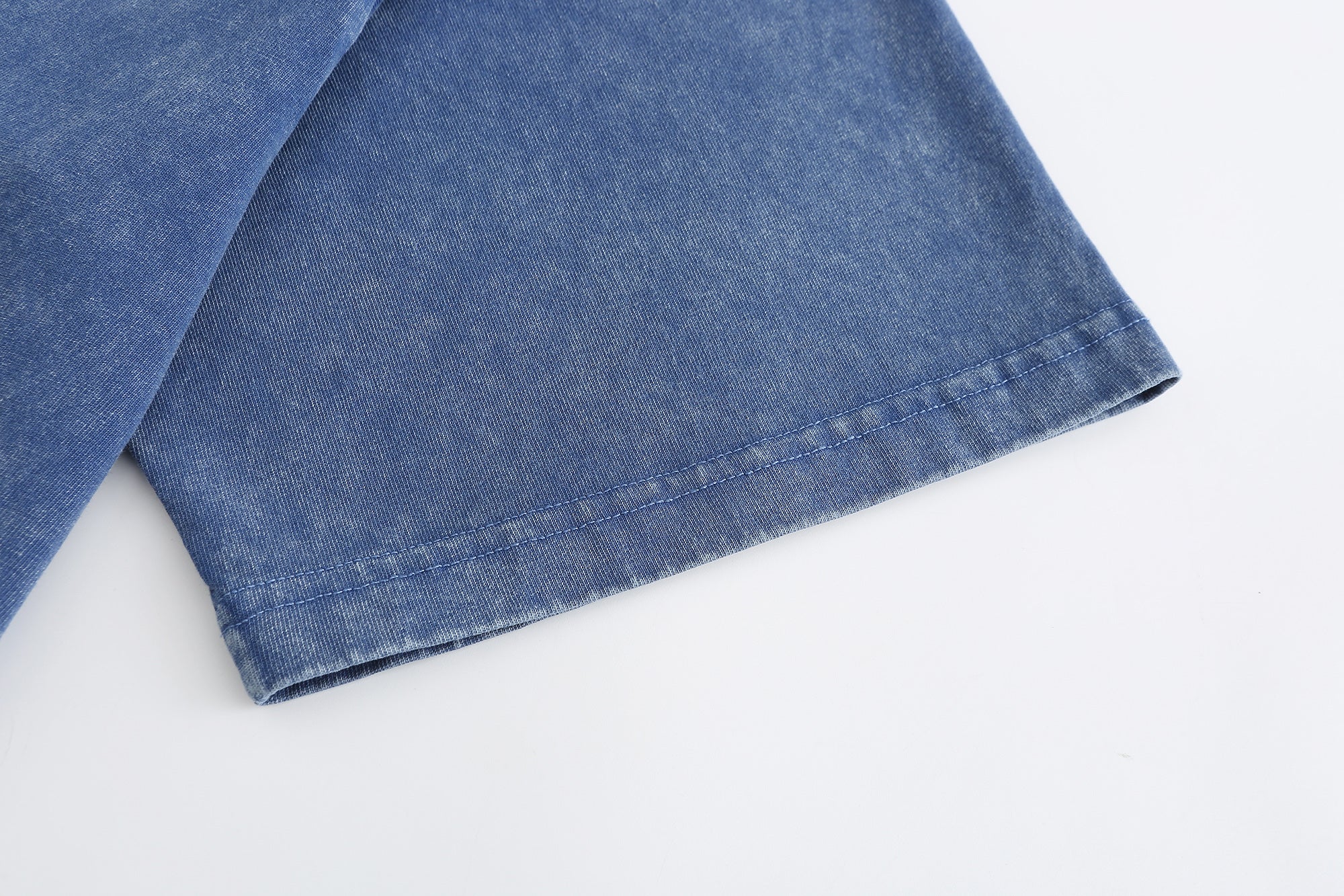 Blue vintage washed T-shirt sleeve detail showing cotton texture and seam finish